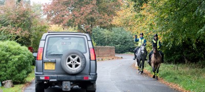 horse riders passing by car